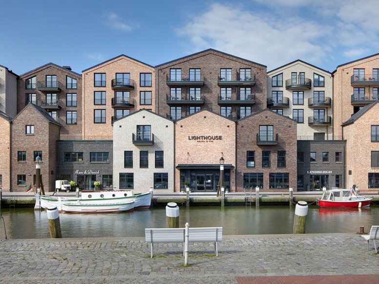 Lighthouse Hotel & Spa in Büsum Havenbekken met boten; aan de overkant van de oever staan moderne bakstenen huizen